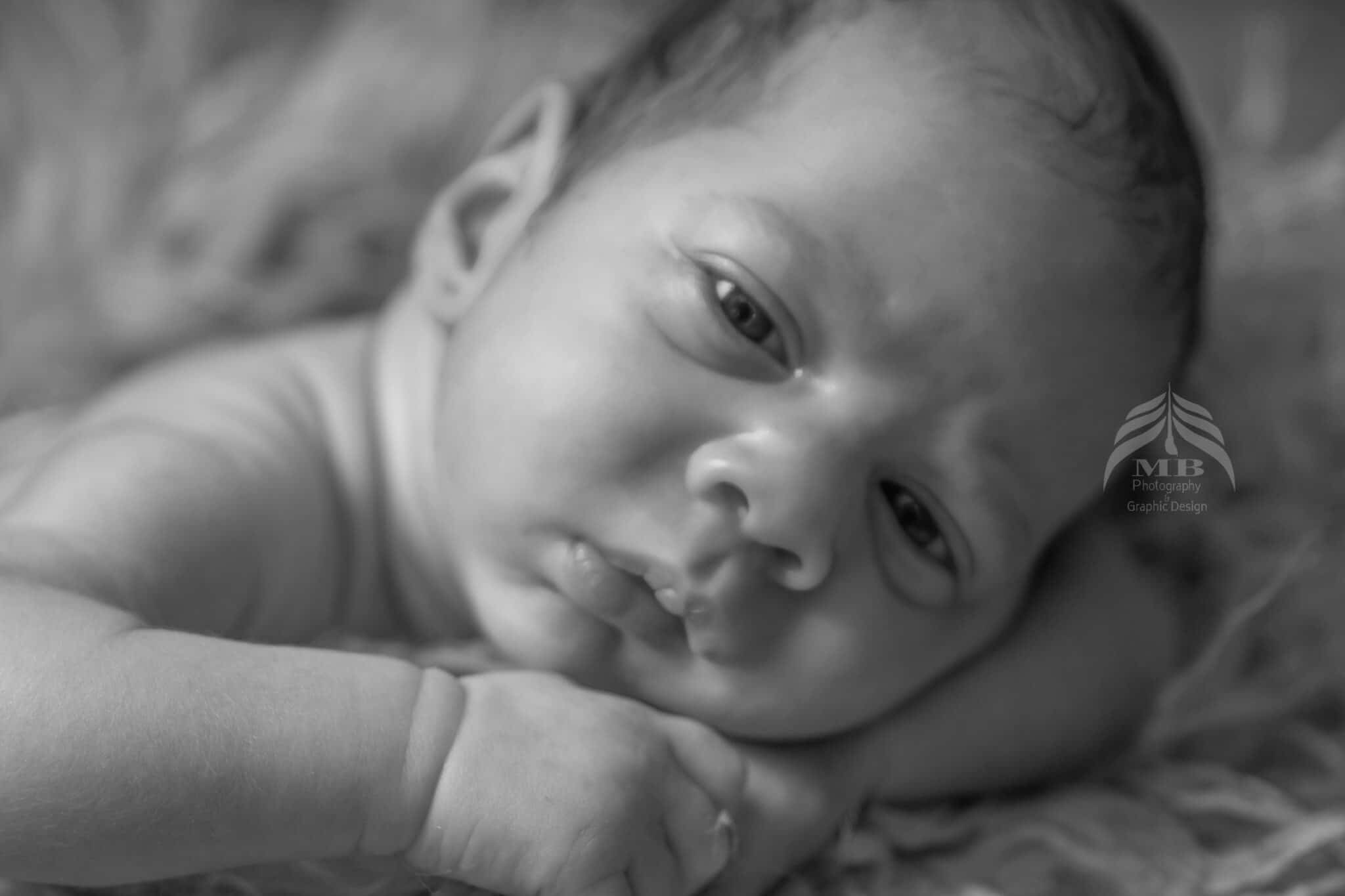 Photography Portfolio 1 Mariam Cheaitou Bazzi Photography Portfolio in Windsor Black-and-white close-up portrait of an awake newborn baby resting gently on a soft textured blanket during a photography session in Windsor, Ontario.