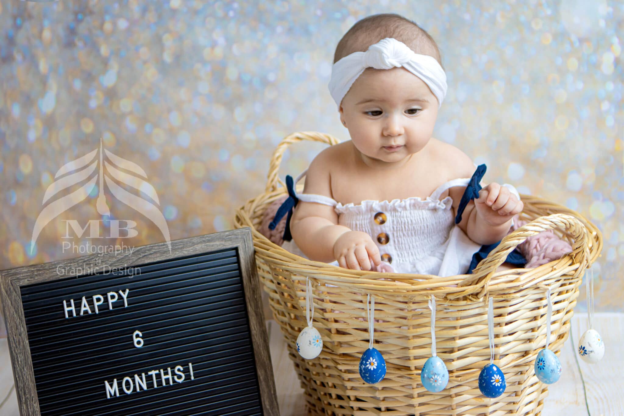 Photography Portfolio 37 Mariam Cheaitou Bazzi Photography Portfolio in Windsor Six-month-old baby girl sitting in a wicker basket decorated with painted Easter eggs during a milestone photography session in Windsor, Ontario.