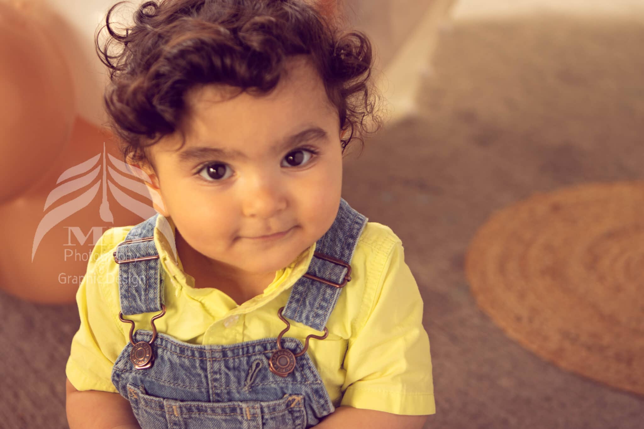 Photography Portfolio 33 Mariam Cheaitou Bazzi Photography Portfolio in Windsor Close-up of smiling one year old boy with curly hair in yellow shirt and overalls, milestone photography by Windsor Ontario photographer