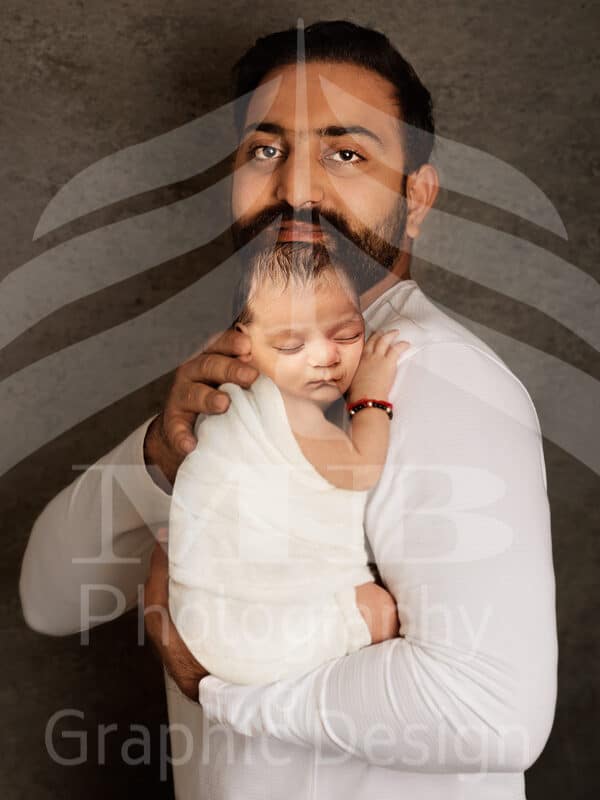 Photography Portfolio 57 Mariam Cheaitou Bazzi Photography Portfolio in Windsor Father gently embracing his sleeping newborn baby boy during an intimate studio newborn photography session in Windsor, Ontario.