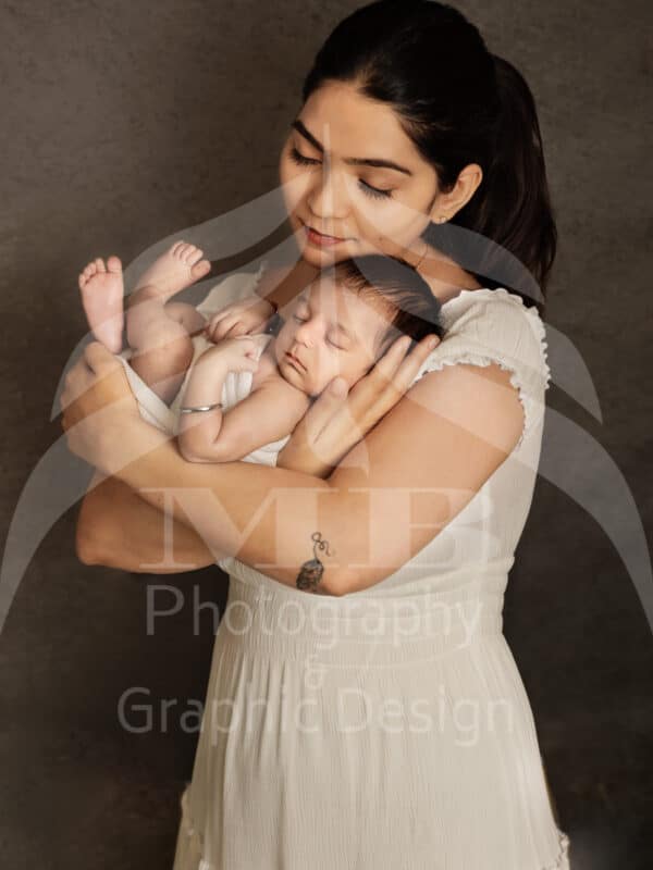 Photography Portfolio 58 Mariam Cheaitou Bazzi Photography Portfolio in Windsor Mother gently embracing her sleeping newborn baby boy during an intimate studio newborn photography session in Windsor, Ontario.