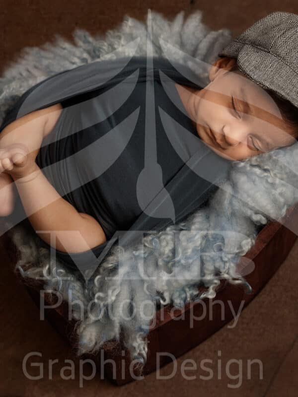 Photography Portfolio 23 Mariam Cheaitou Bazzi Photography Portfolio in Windsor Sleeping newborn baby boy wrapped in dark grey and wearing a matching flat cap, posed safely in a wooden bowl with a soft fur layer during a studio photography session in Windsor, Ontario.