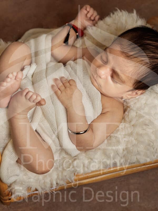 Photography Portfolio 22 Mariam Cheaitou Bazzi Photography Portfolio in Windsor Sleeping newborn baby wrapped in soft white fabric and posed safely on a small wooden bed with a textured cream layer during a studio photography session in Windsor, Ontario.