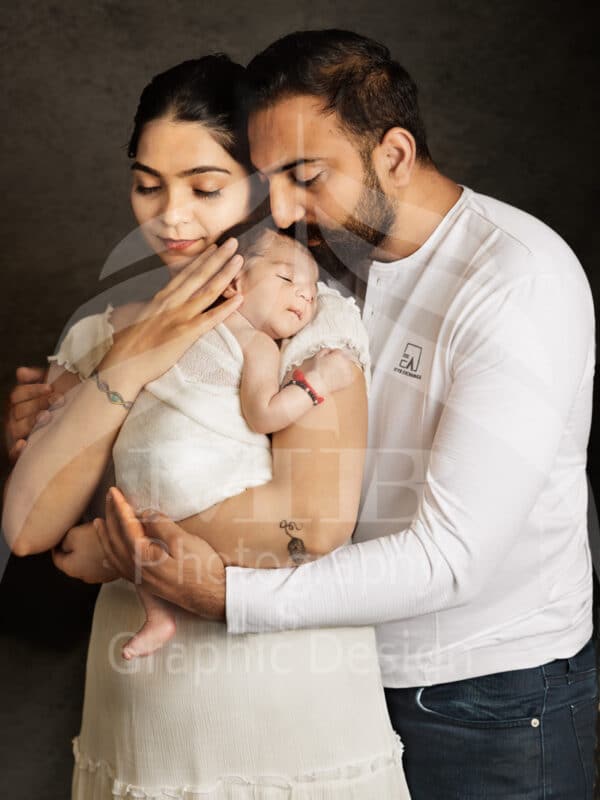 Photography Portfolio 54 Mariam Cheaitou Bazzi Photography Portfolio in Windsor Mother and father gently embracing their sleeping newborn baby during an intimate studio family photography session in Windsor, Ontario.