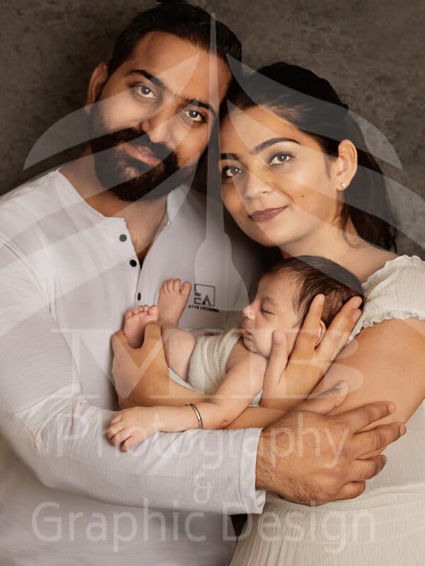 Photography Portfolio 55 Mariam Cheaitou Bazzi Photography Portfolio in Windsor Mother and father standing close together while gently holding their sleeping newborn baby during a studio family photography session in Windsor, Ontario.