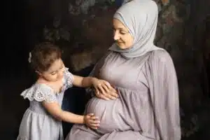 A moment between mother and daughter bonding with her unborn child. Mom is pregnant. 