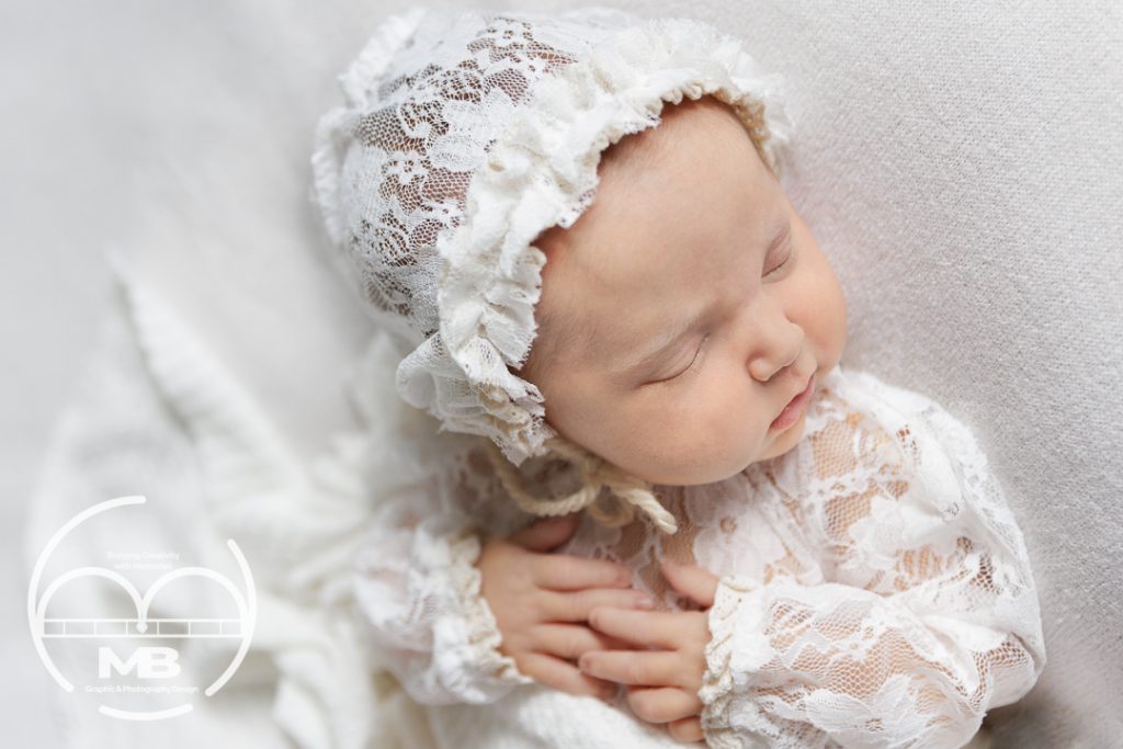 Model Call 1 Mariam Cheaitou Bazzi Sleeping newborn wearing a white lace bonnet and outfit in a soft studio portrait session in Windsor, Ontario.